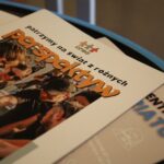 Broszura ze zdjęciem na okładce przedstawiającym grupę ludzi wchodzących w interakcje na świeżym powietrzu. Polski tytuł brzmi patrzymy na świat z różnych perspektyw.