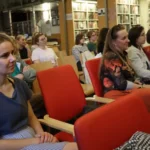 Publiczność siedząca w bibliotece podczas prezentacji.
